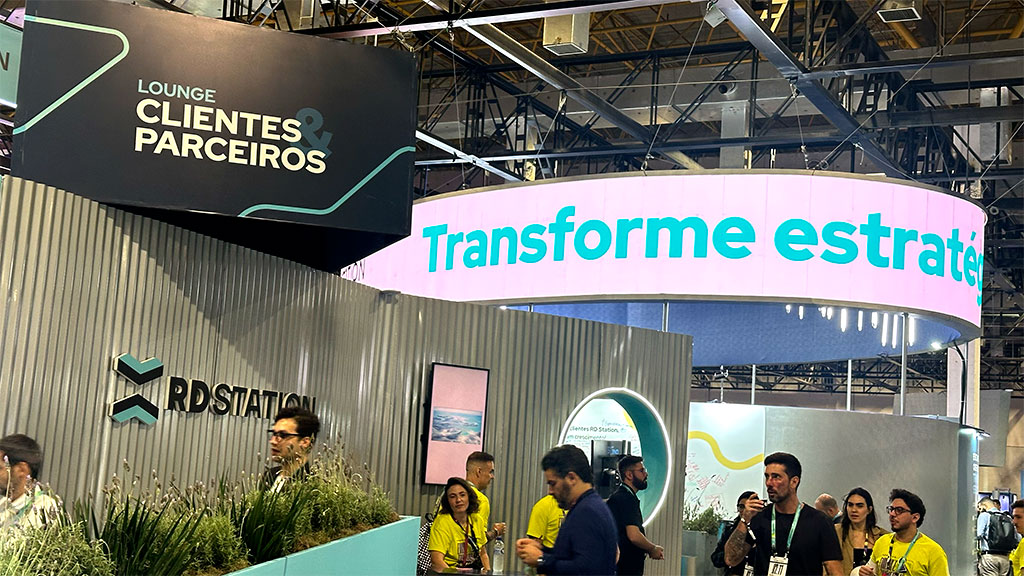 Lounge de clientes e parceiros no RD Summit 2024, com visitantes explorando o espaço interativo da RD Station