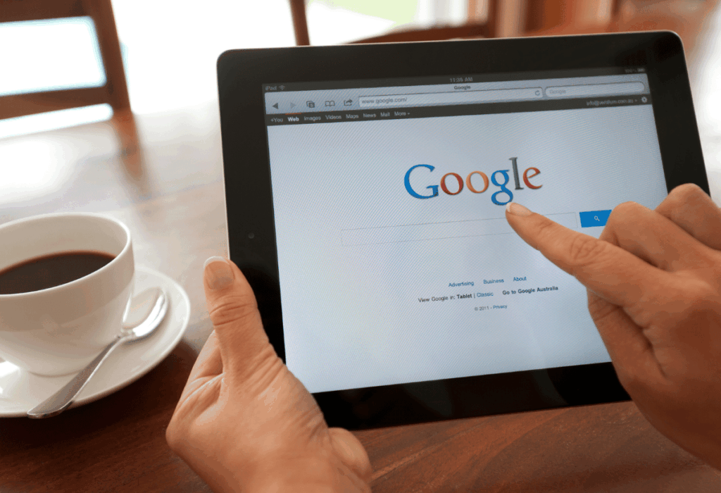 Pessoa usando tablet para fazer uma busca no Google, representando o comportamento moderno de pesquisa na internet.